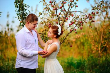 Bir elma ağacı dalları altında duran elma bahçesi içinde gelin ve damat öpüşme