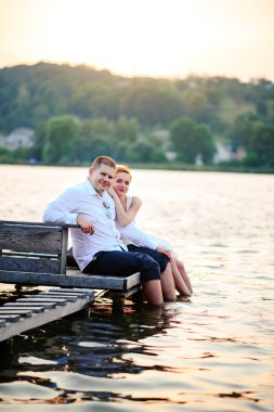 Güzel genç düğün çift, gelin ve damat Gölü arka plan üzerinde poz. Damat ve gelin pier üzerine