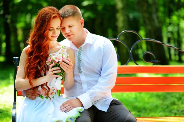 De bruid en bruidegom zitten op een bankje — Stockfoto