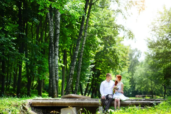 Groom fixe son noeud papillon bleu debout devant la mariée sur un vieux pont de pierre — Photo