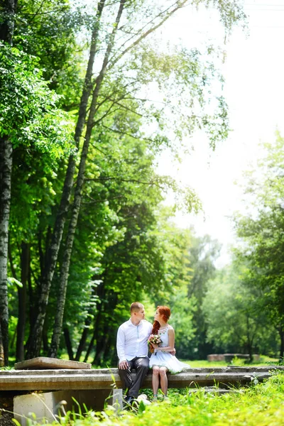 Groom corrige seu laço azul em pé diante da noiva na ponte de pedra velha — Fotografia de Stock