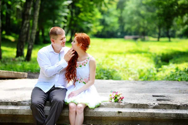 Groom fixes his blue bow tie standing before the bride on old stone bridge — Stock Photo, Image