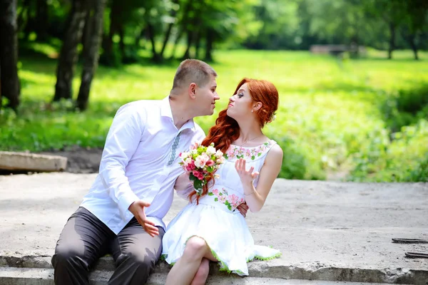 Groom fixe son noeud papillon bleu debout devant la mariée sur un vieux pont de pierre — Photo