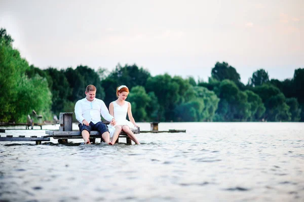 Красивая молодая супружеская пара, невеста и жених позируют на фоне озера. Жених и невеста на пирсе — стоковое фото
