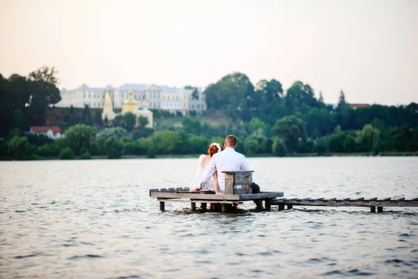 Beautiful young wedding couple, bride and groom posing on lake background. The groom and the bride on pier — Stock Photo, Image