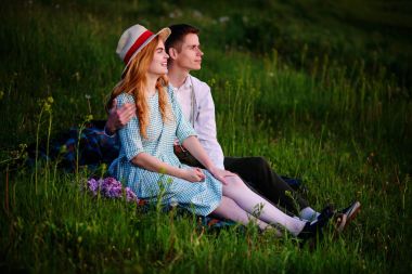 Genç çift ekose parkta oturan ve gün batımında bak