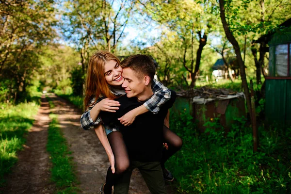 Portret van de jonge man die geeft mooie vrouw piggyback — Stockfoto