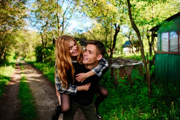 Portret van de jonge man die geeft mooie vrouw piggyback — Stockfoto