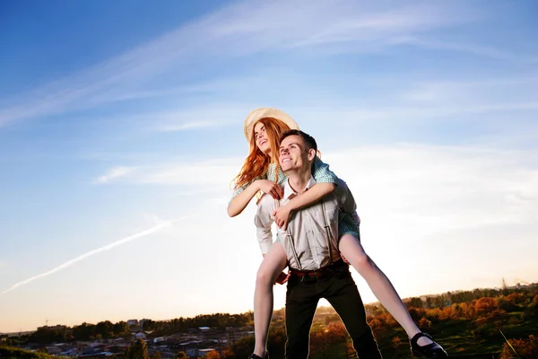 Jovem piggybacking sua namorada feliz com a mão levantada. Amantes alegres sonhando — Fotografia de Stock