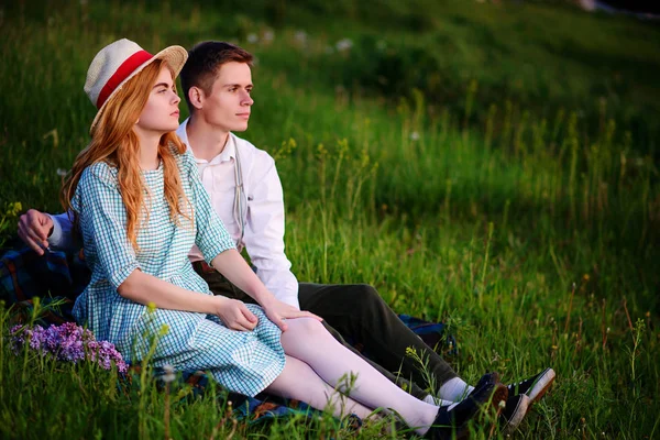 Genç çift ekose parkta oturan ve gün batımında bak