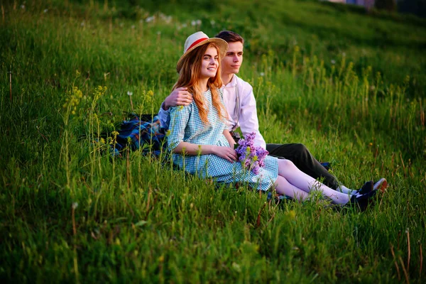 Jovem casal sentado no xadrez no parque e olhar para o pôr do sol — Fotografia de Stock