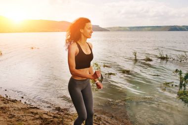 Güzel sportif kadın runing spor giyim bir göl kıyısında. Kız egzersiz