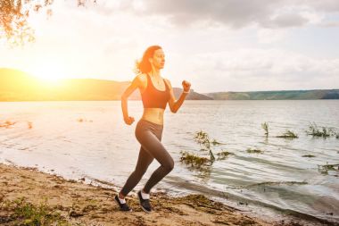 Güzel sportif kadın runing spor giyim bir göl kıyısında. Kız egzersiz
