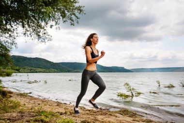 Güzel sportif kadın runing spor giyim bir göl kıyısında. Kız egzersiz