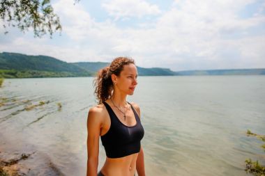 Güzel bir sportif kadın spor giyim bir göl kıyısında duran ve bir egzersiz için hazırlanıyor