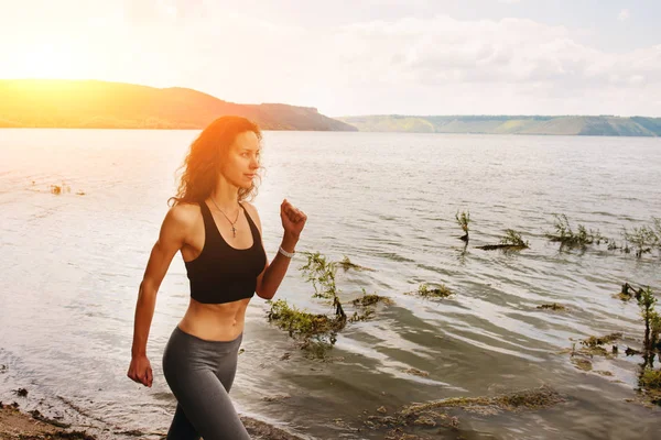 Güzel sportif kadın runing spor giyim bir göl kıyısında. Kız egzersiz