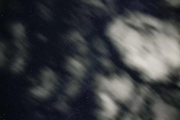 Fundo do céu noturno azul escuro com inúmeras estrelas cintilantes e nuvens brancas em movimento sobre ele — Fotografia de Stock