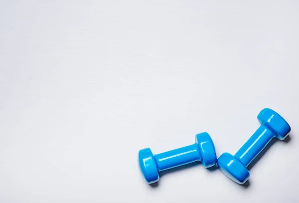 Two dumbbells of blue are lying on a white background with a tree texture — Stock Photo, Image