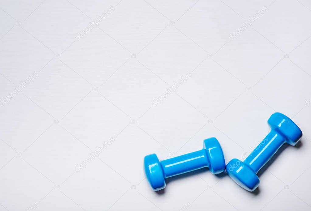 Two dumbbells of blue are lying on a white background with a tree texture
