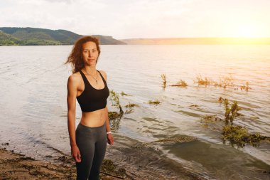 Güzel bir sportif kadın spor bir göl kıyısında ayakta