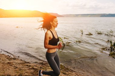 Spor bir göl kıyısında güzel sportif kadın runing