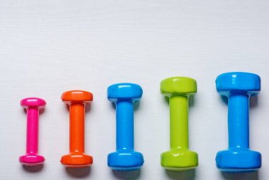 birçok mavi yeşil ve beyaz bir arka plan üzerinde orta dumbbells bir turuncu, kavram, fitness hazırlama ekipmanları üstten görünüm sahte kadar spor