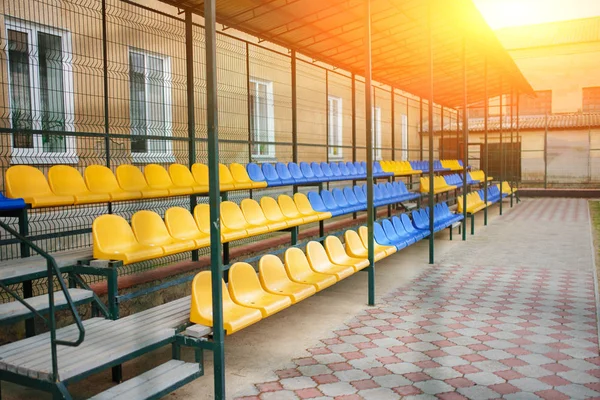 Assentos esportivos azuis e amarelos vazios do grande estande no quintal da escola no estádio — Fotografia de Stock