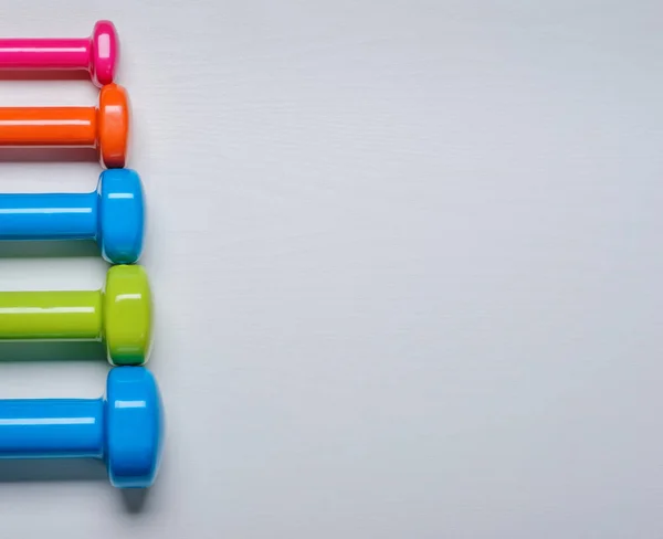 Viele blaue grüne und eine orangefarbene in der Mitte Hanteln auf weißem Hintergrund, Konzept zur Vorbereitung von Fitnessgeräten von oben — Stockfoto