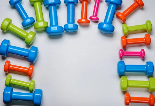 Viele blaue grüne und eine orangefarbene in der Mitte Hanteln auf weißem Hintergrund, Konzept zur Vorbereitung von Fitnessgeräten von oben — Stockfoto