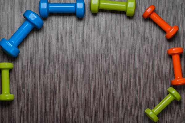 Muitos azul verde e uma laranja nos halteres do meio em um fundo, conceito se preparando para fitness equipamentos esportivos vista superior mock up — Fotografia de Stock