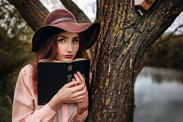 Meisje-student zitten op het gazon en luidt leerboek — Stockfoto