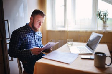 Evde biraz evrak işi yapan yakışıklı erkek.