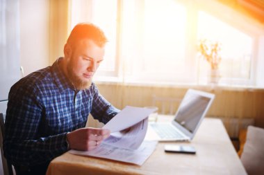 Evde biraz evrak işi yapan yakışıklı erkek.