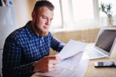 Evde biraz evrak işi yapan yakışıklı erkek.