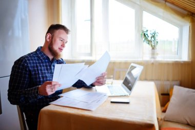 Evde iş adamı, evrak ve faturaları kontrol ile bir dizüstü bilgisayar, çalışıyor.