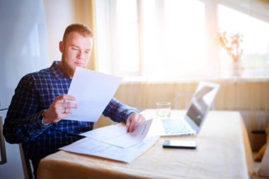 Evde iş adamı, evrak ve faturaları kontrol ile bir dizüstü bilgisayar, çalışıyor.