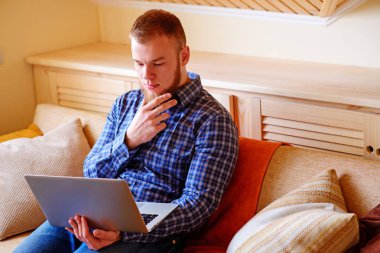 dizüstü bilgisayarınızda evde absorbe çalışan genç adam.