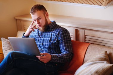 dizüstü bilgisayarınızda evde absorbe çalışan genç adam.