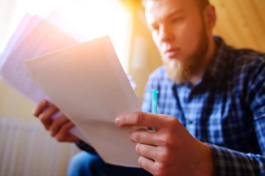 Genç yakışıklı adam kanepede oturan ve bir çalışma kağıdı saatler.