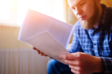 Genç yakışıklı adam kanepede oturan ve bir çalışma kağıdı saatler.