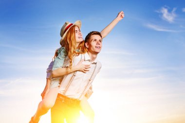 Mutlu kız arkadaşıyla yükseltilmiş el piggybacking genç adam. Neşeli severler rüya.