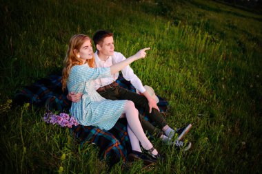 Genç çift, park ve günbatımı bakmak ekose oturan kadın ufuk işaret ediyor.