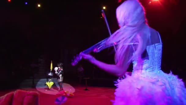 Блондинка, играющая на скрипке в вечернем платье. Фокусник-мужчина показывает фокус с превращением шарика в белого голубя . — стоковое видео