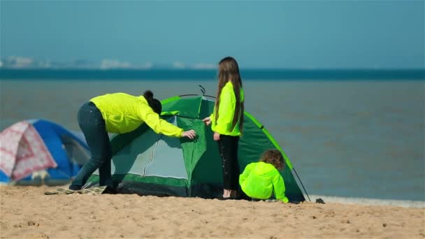 Mutter mit Kindern bereitet ein Zelt am Strand für Familien vor. — Stockvideo