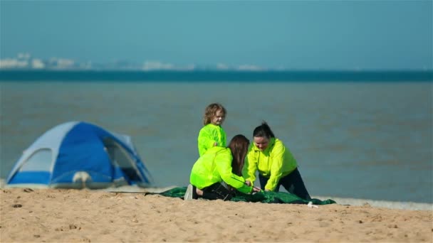 Young scouts and the coach set a tent on the shore of the lake. — Stockvideo