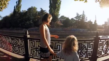 Ağır çekim. Şirin çocuklar ve Şehir Parkı içinde nehir kıyısında yürüyen kız .