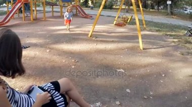 Ağır çekim. Akıllı telefonundaki parkta oynayan kız