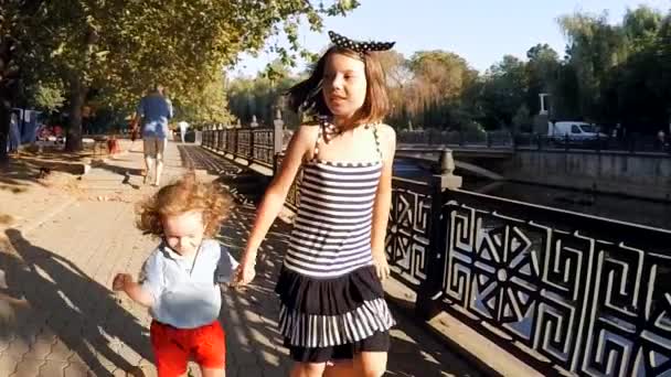 Lento movimiento. lindo niños hermano y hermana caminando por el río en el parque de la ciudad  . — Vídeo de stock