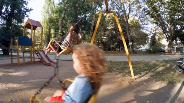 Kinderen rijden op een schommel op de site — Stockvideo