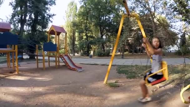 Lento movimiento. Los niños montan en los columpios — Vídeo de stock